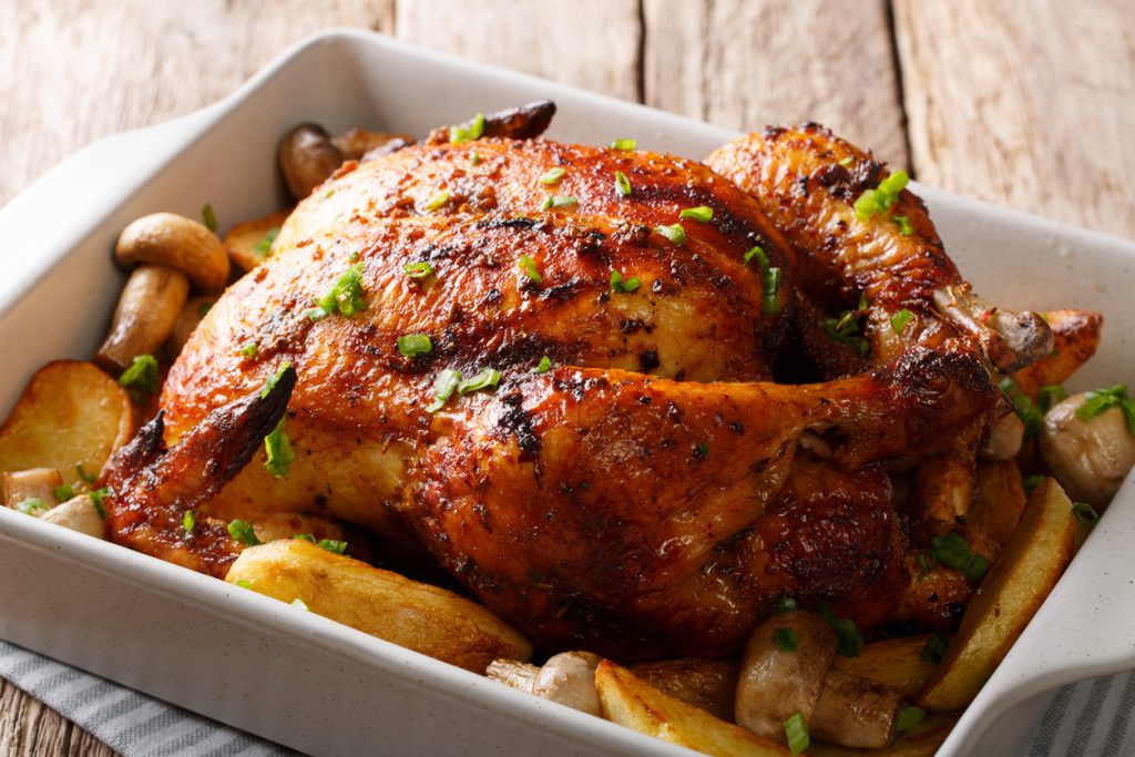 grilled chicken with mushrooms and potatoes close-up in a baking dish. horizontal